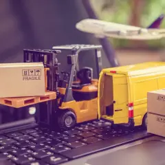 Miniatura wózka widłowego, żółtej furgonetki i samolotu na klawiaturze z pudełkami.