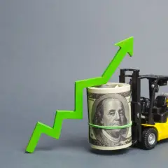 Żółty wózek widłowy podnosi zwinięty banknot dolarowy z zieloną strzałką wzrostu.