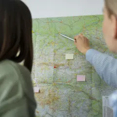 Dwie kobiety analizują mapę, jedna wskazuje palcem trasę.